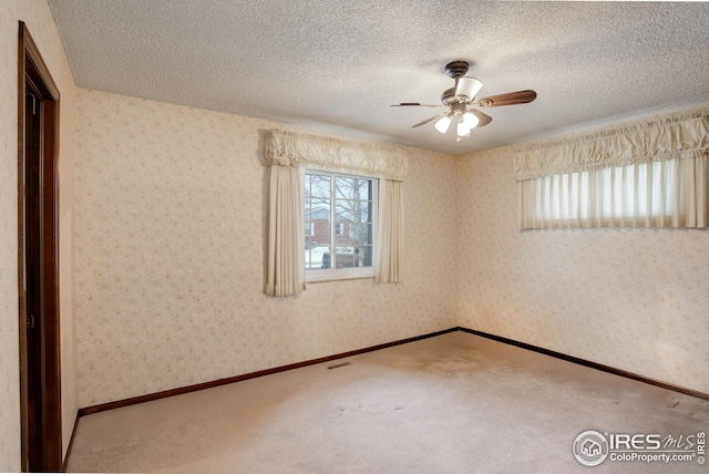 empty room with ceiling fan, carpet floors, and a textured ceiling