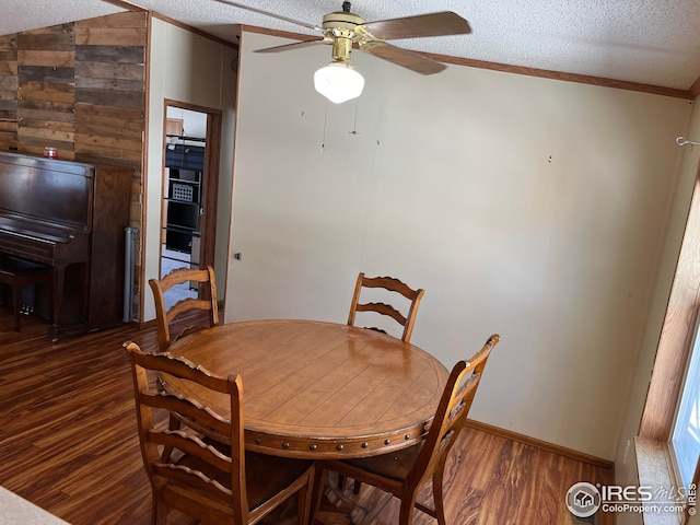 dining area with lofted ceiling, dark wood-type flooring, ceiling fan, ornamental molding, and a textured ceiling