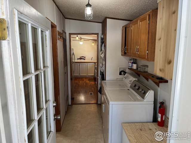 clothes washing area featuring cabinets, ceiling fan, ornamental molding, a textured ceiling, and washing machine and clothes dryer