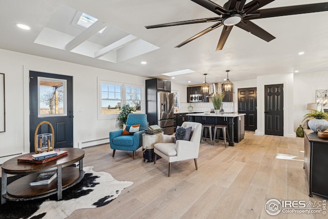 living room with light wood-type flooring, a baseboard radiator, a ceiling fan, and recessed lighting