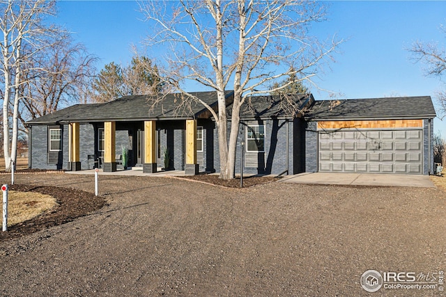 single story home with a garage, dirt driveway, and brick siding