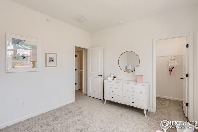 bedroom with light colored carpet, a walk in closet, and a closet