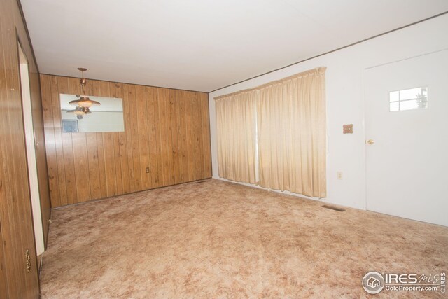 spare room featuring light carpet and wooden walls