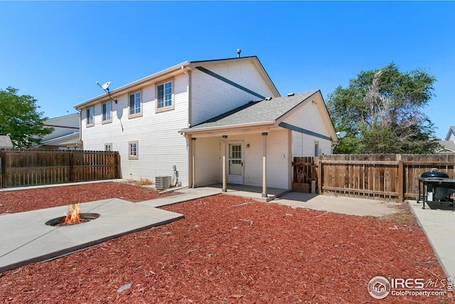 back of property with a fire pit, central AC unit, and a patio