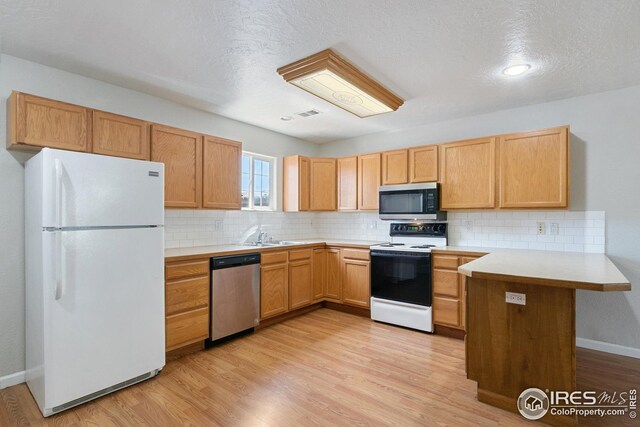 kitchen featuring kitchen peninsula, light hardwood / wood-style flooring, and stainless steel appliances