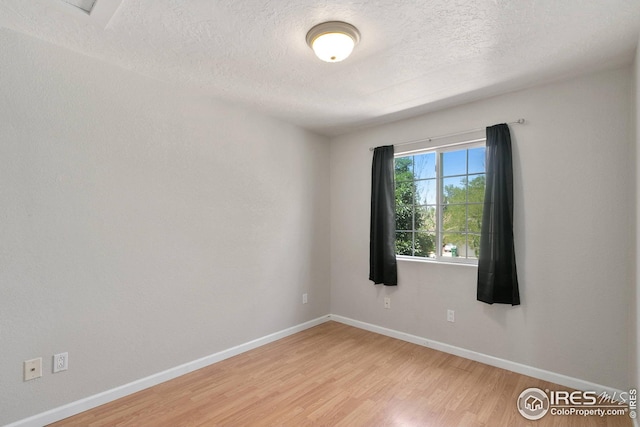 spare room featuring wood-type flooring and a textured ceiling