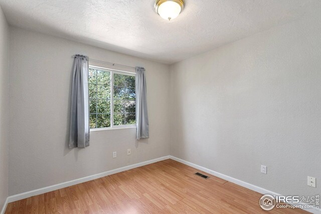 unfurnished room with wood-type flooring and a textured ceiling