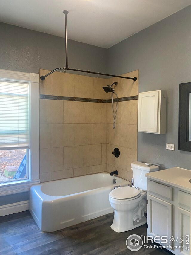 full bathroom with toilet, tiled shower / bath combo, wood-type flooring, and vanity