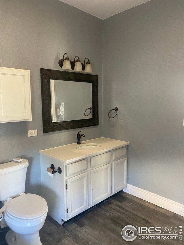 bathroom with toilet, vanity, and hardwood / wood-style flooring