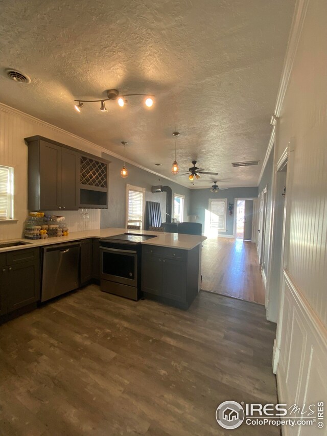 kitchen featuring kitchen peninsula, appliances with stainless steel finishes, dark hardwood / wood-style floors, a textured ceiling, and crown molding