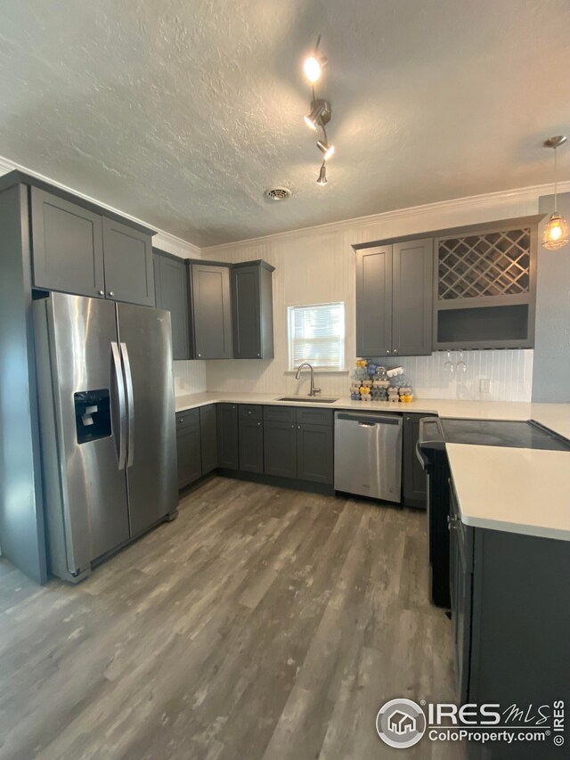 kitchen featuring pendant lighting, dark wood-type flooring, stainless steel appliances, sink, and ornamental molding