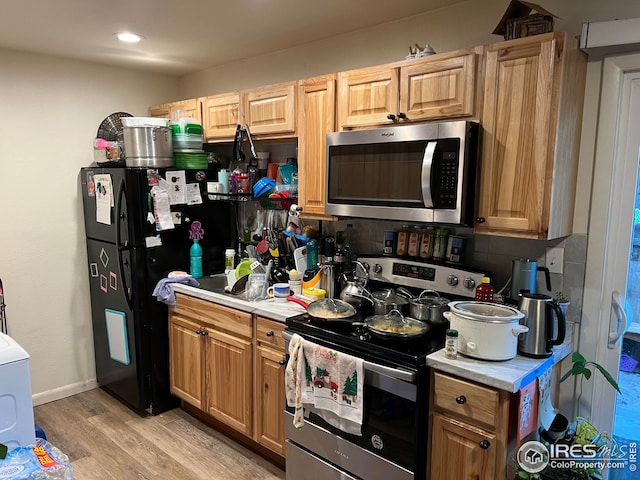 kitchen with light wood-type flooring, stainless steel appliances, washer / clothes dryer, and tasteful backsplash