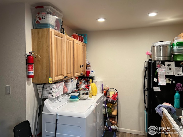 washroom with washing machine and clothes dryer, cabinets, and wood-type flooring