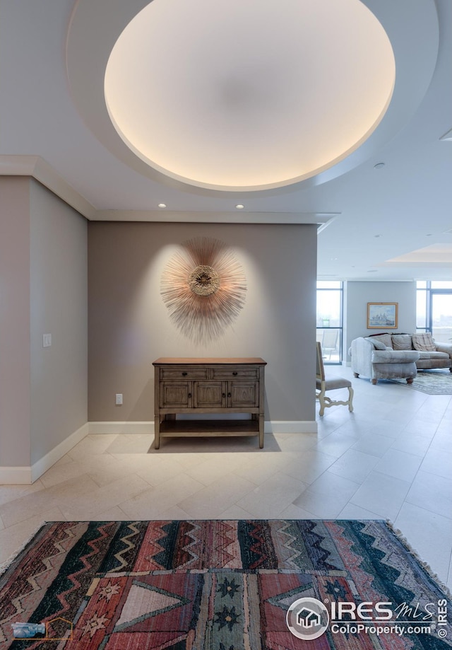 hallway with a healthy amount of sunlight, a tray ceiling, and light tile patterned floors