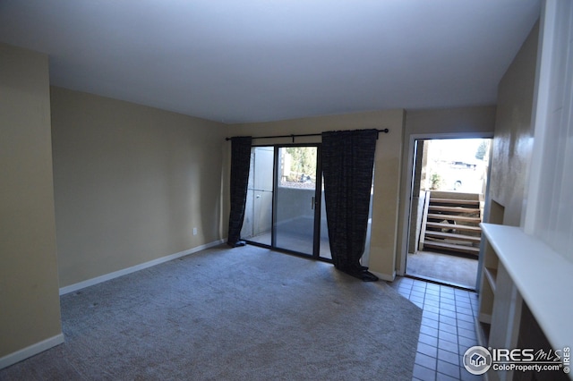 carpeted empty room featuring tile patterned flooring and baseboards