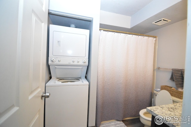 clothes washing area featuring laundry area, visible vents, and stacked washer / drying machine