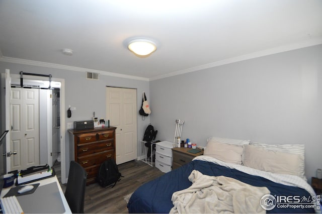 bedroom with a closet, visible vents, wood finished floors, and ornamental molding