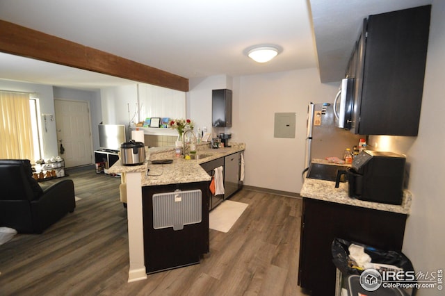 kitchen with dark wood finished floors, appliances with stainless steel finishes, a peninsula, a sink, and beam ceiling