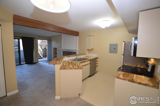 kitchen with butcher block countertops, light colored carpet, a sink, and dishwasher