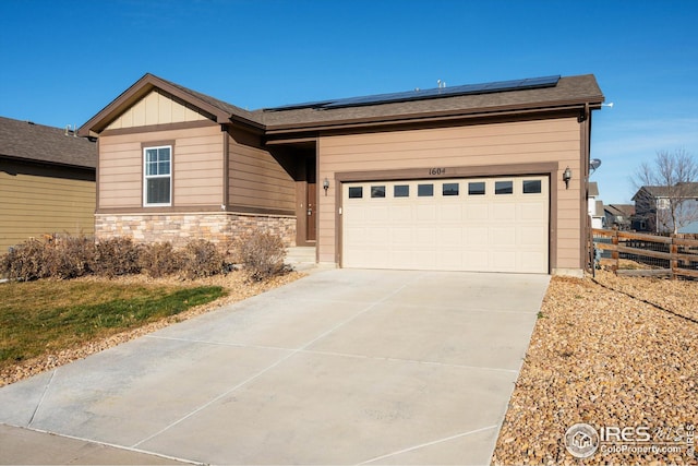 1604 Sorenson Dr, Windsor, CO 80550 - view of front facade featuring driveway, stone siding, an attached garage, fence, and solar panels