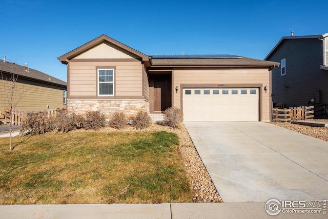 1604 Sorenson Dr, Windsor, CO 80550 - single story home featuring roof mounted solar panels, a front lawn, concrete driveway, stone siding, and a garage