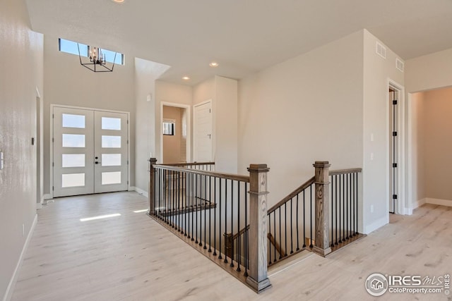 foyer entrance featuring an inviting chandelier, light hardwood / wood-style flooring, and french doors