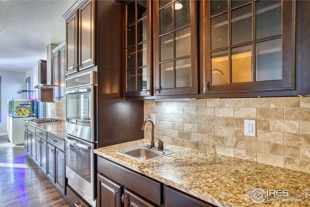 kitchen featuring backsplash, light stone counters, sink, and dark wood-type flooring