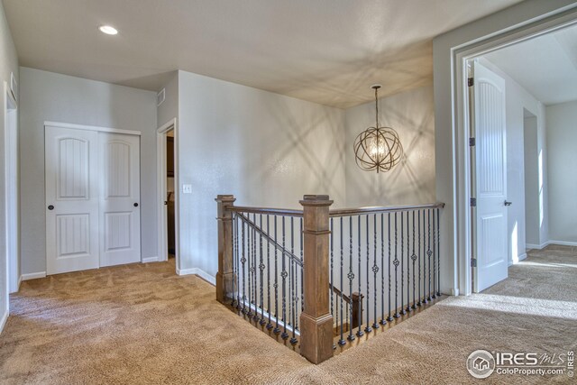 hallway with carpet flooring and an inviting chandelier