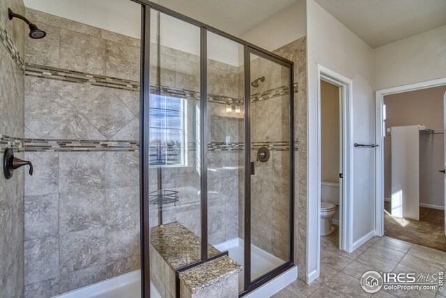 bathroom featuring tile patterned flooring, toilet, and an enclosed shower