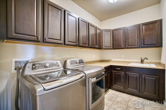 laundry area with separate washer and dryer, sink, cabinets, and a textured ceiling