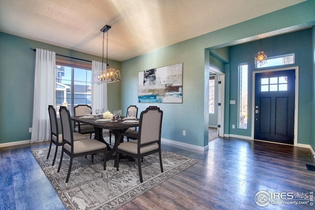 dining area featuring dark hardwood / wood-style flooring, a textured ceiling, and a notable chandelier