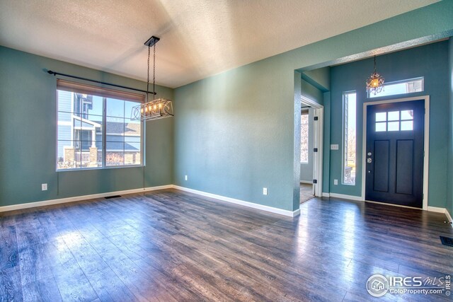 foyer with a notable chandelier, dark hardwood / wood-style floors, and a textured ceiling