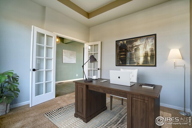 carpeted office featuring a raised ceiling and french doors