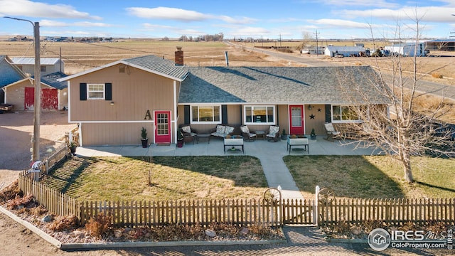 ranch-style house with a patio area, outdoor lounge area, a front lawn, and a rural view