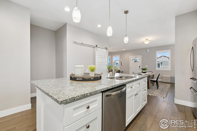 kitchen with stainless steel appliances, baseboards, a sink, and a barn door