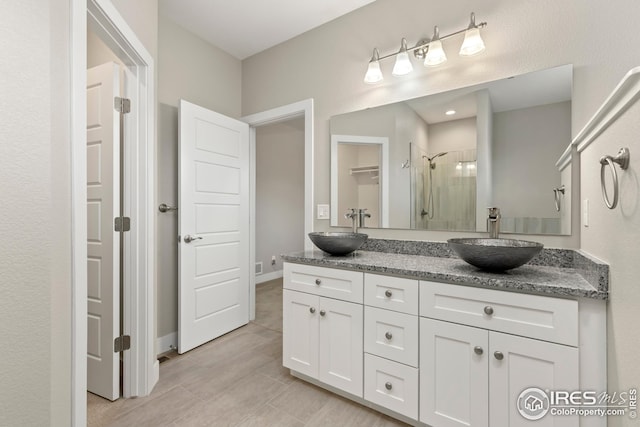 full bathroom with a stall shower, double vanity, and a sink