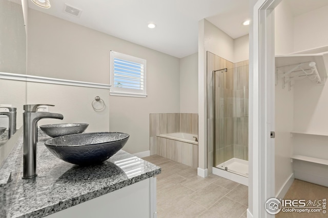 full bathroom with a sink, visible vents, a stall shower, a bath, and a walk in closet
