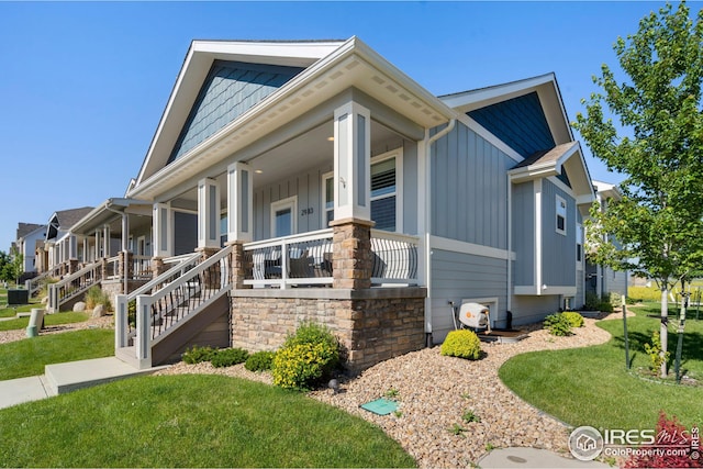 view of front of home with board and batten siding, a porch, a front yard, and stairway