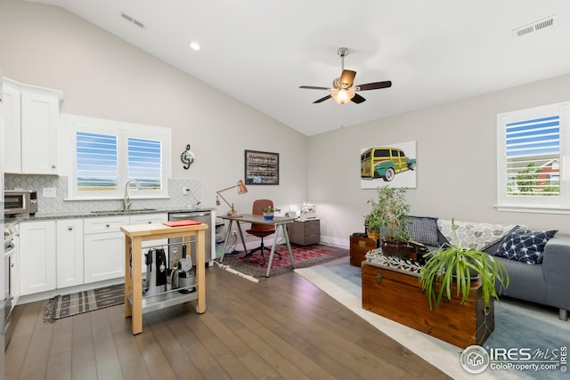 interior space with a sink, ceiling fan, lofted ceiling, visible vents, and wood finished floors