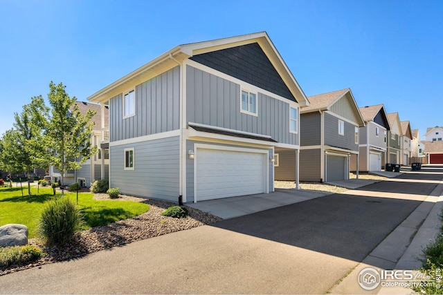 view of side of home featuring concrete driveway, board and batten siding, a residential view, and an attached garage