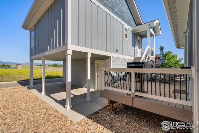 view of home's exterior with board and batten siding, a wooden deck, and a patio