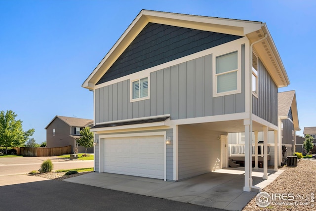 view of front of property with board and batten siding, an attached garage, and central AC