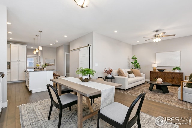 dining space featuring recessed lighting, dark wood-style flooring, ceiling fan, and a barn door