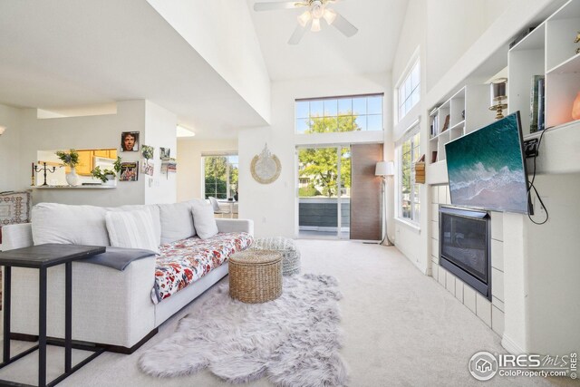 living room featuring a tile fireplace, light colored carpet, high vaulted ceiling, and ceiling fan