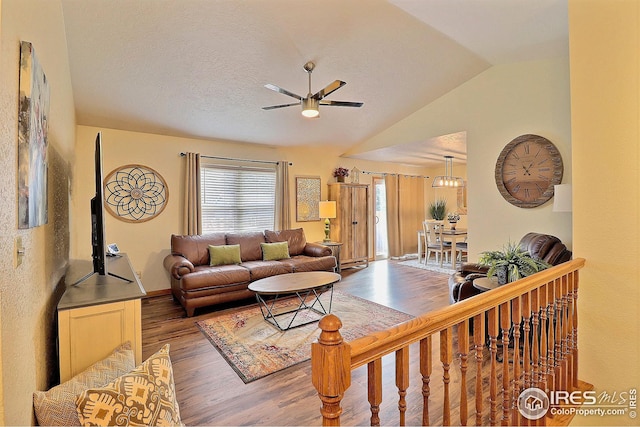 living room featuring lofted ceiling, dark wood-type flooring, a textured ceiling, and ceiling fan