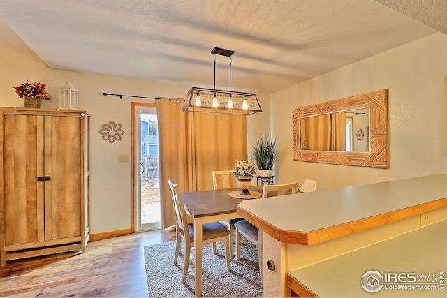 dining area with plenty of natural light, light hardwood / wood-style floors, and a textured ceiling