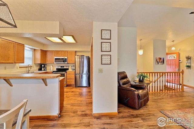 kitchen featuring sink, stainless steel appliances, a kitchen breakfast bar, decorative light fixtures, and kitchen peninsula