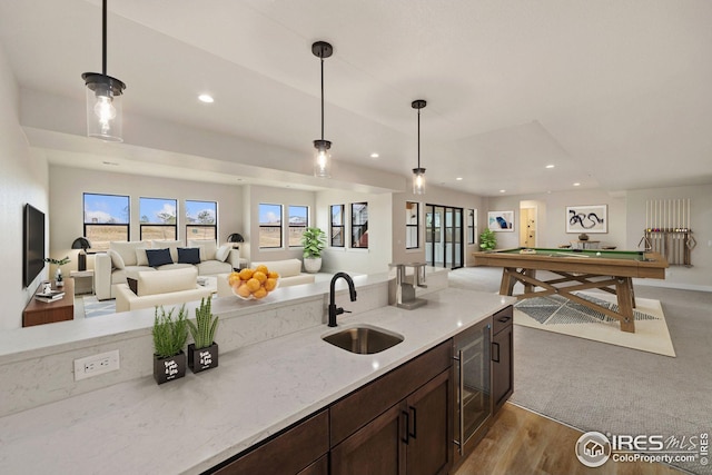 kitchen with light stone countertops, decorative light fixtures, pool table, and sink