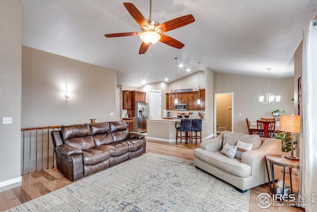 living room with ceiling fan with notable chandelier, light hardwood / wood-style floors, and high vaulted ceiling