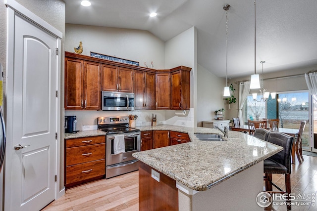 kitchen featuring an inviting chandelier, sink, decorative light fixtures, a kitchen bar, and stainless steel appliances